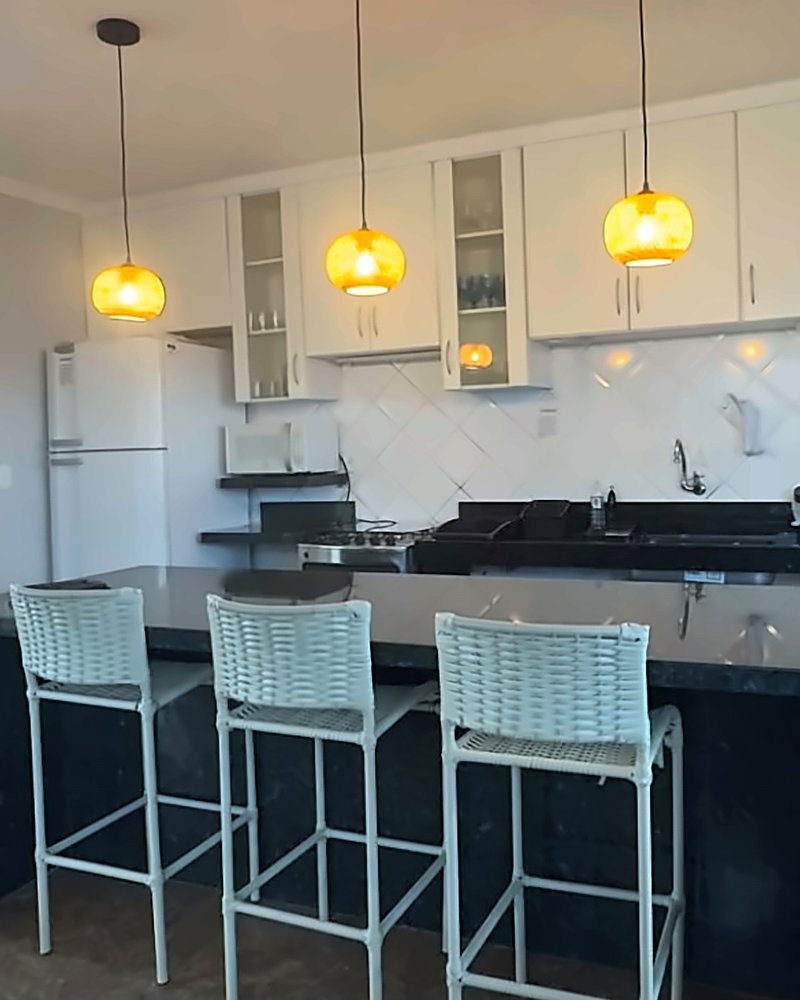 Cozinha do piso superior com ilha de granito preto, banquetas e pendentes